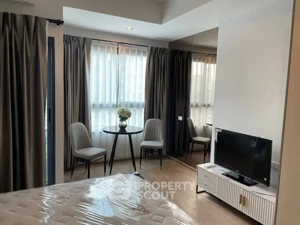 Modern bedroom with natural light, featuring a cozy seating area and stylish decor.
