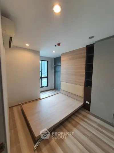 Modern bedroom with foldable bed and wooden flooring, maximizing space and functionality.