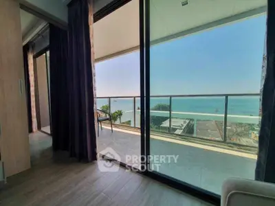 Stunning ocean view from modern balcony with glass railing and cozy seating area.