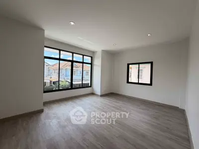 Spacious empty room with large windows and wooden flooring, perfect for customization.