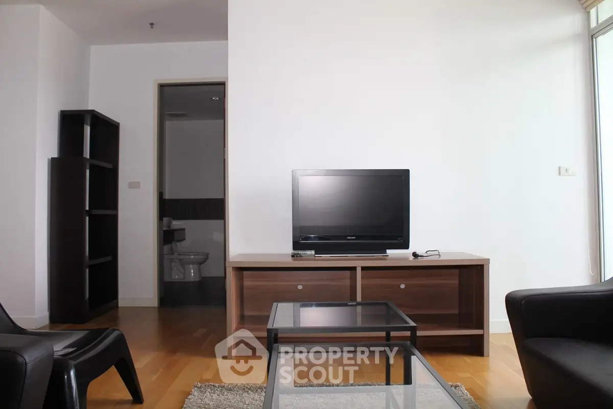 Modern living room with sleek furniture and TV, showcasing minimalist design and natural light.