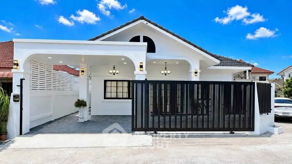 Charming single-story white house with modern gate and spacious driveway under a clear blue sky.