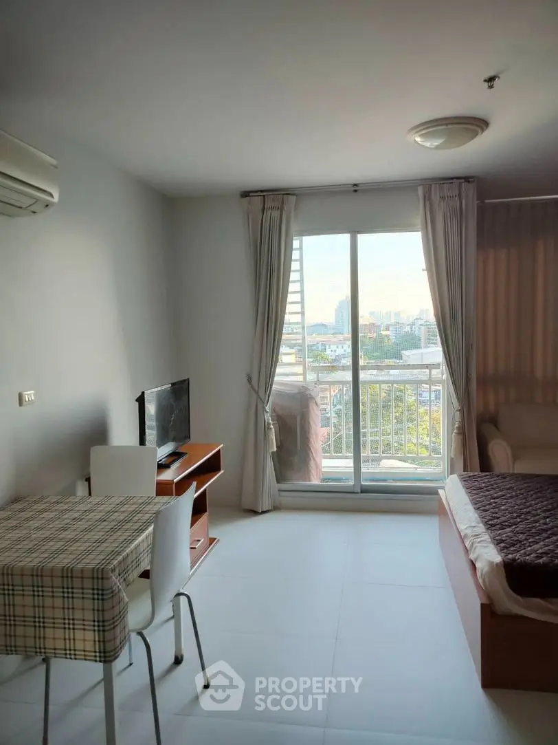 Bright studio apartment with city view, featuring a cozy living area and modern furnishings.