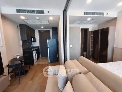 Modern studio apartment with open layout, featuring a cozy living area, compact kitchen, and stylish furnishings.