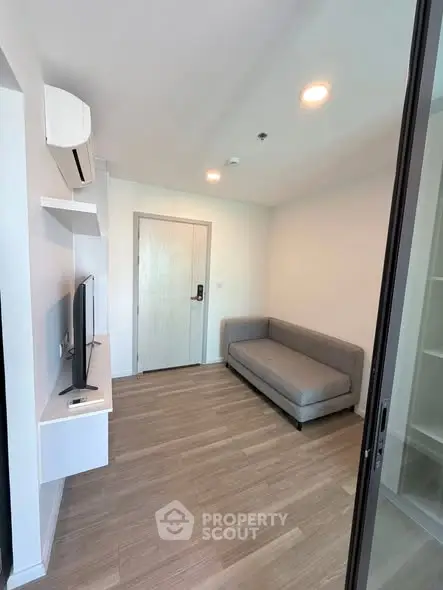 Modern living room with sleek design, featuring a cozy gray sofa and wall-mounted TV, perfect for relaxation.