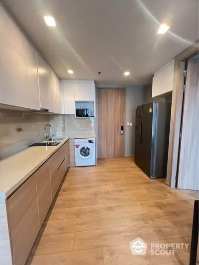 Modern kitchen with sleek cabinetry, washing machine, and spacious layout