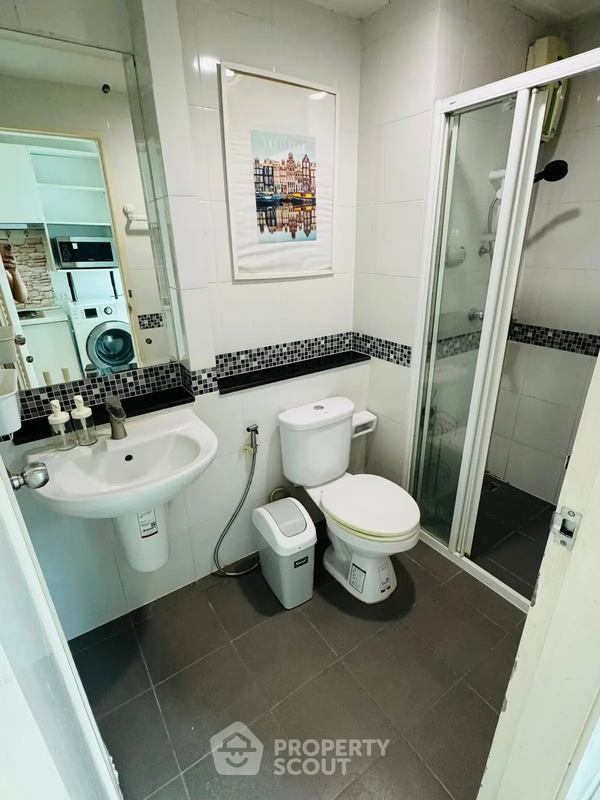 Modern bathroom with shower, toilet, and sink in a compact layout, featuring sleek white tiles and contemporary fixtures.