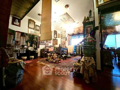 Luxurious living room with elegant decor and hardwood floors, featuring ornate furnishings and a chandelier.