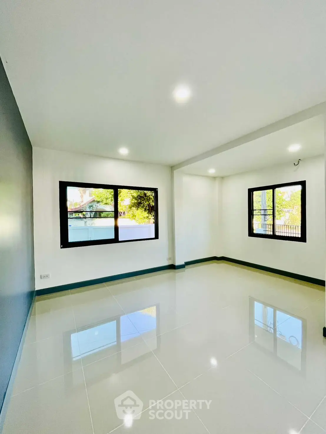 Spacious and bright living room with large windows and glossy tiled floors.