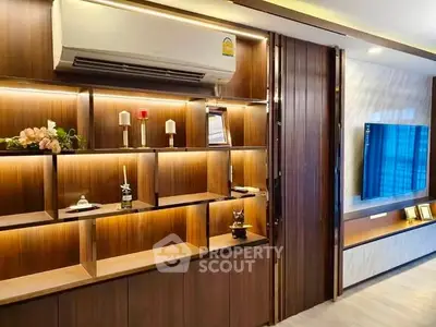 Modern living room with stylish wooden shelving and mounted TV, featuring elegant lighting and decor.