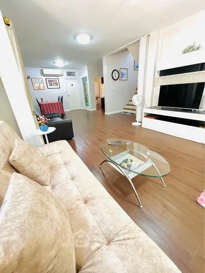 Spacious living room with modern decor and hardwood floors, featuring a cozy sofa and sleek glass coffee table.