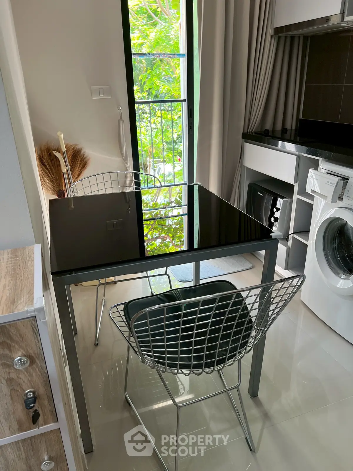 Modern kitchen with sleek black table and chairs, featuring a washing machine and stylish decor.