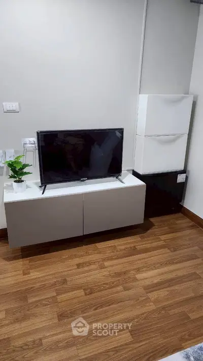 Modern living room with sleek TV setup and stylish wooden flooring.