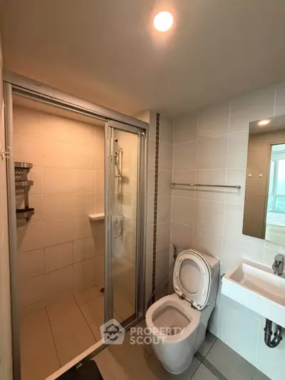 Modern bathroom with shower, toilet, and sink in a sleek tiled design.