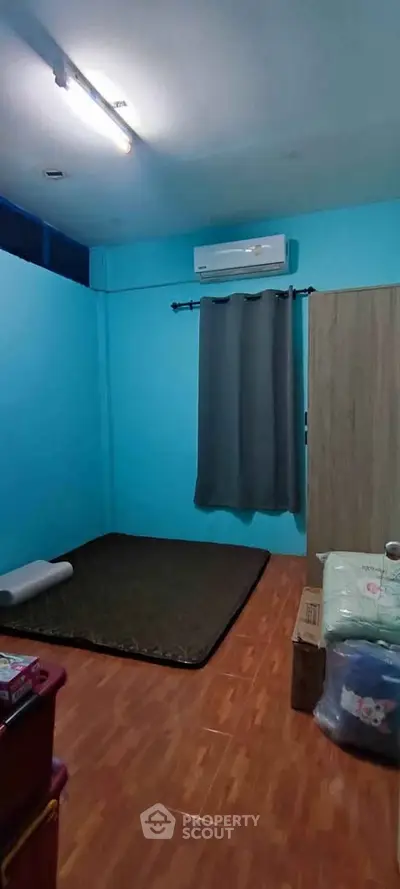 Cozy minimalist bedroom with air conditioning and wooden flooring.