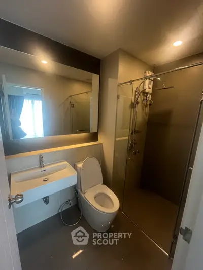 Modern bathroom with glass shower and large mirror in sleek apartment