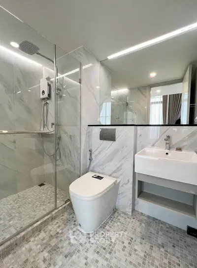 Modern bathroom with glass shower and sleek fixtures in luxury apartment.