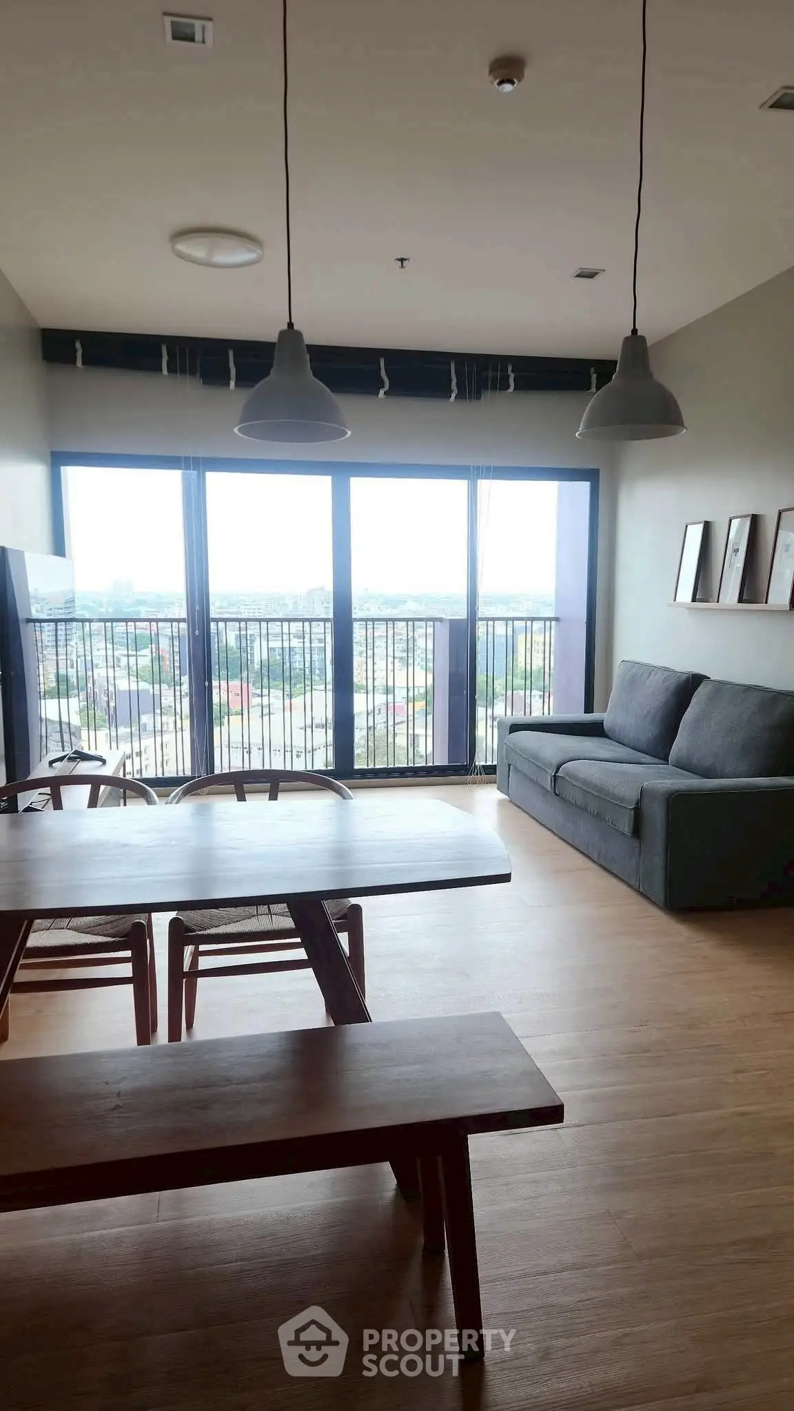 Spacious living room with large windows offering stunning city views, modern furnishings, and ample natural light.