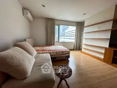 Spacious bedroom with cozy sofa and large window offering city view
