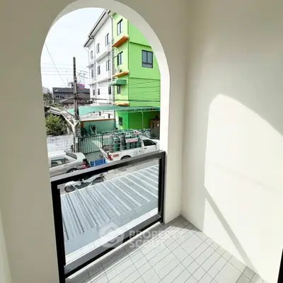 Charming small balcony with arched opening and street view, perfect for relaxation.