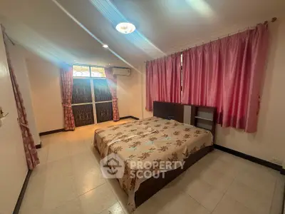 Spacious bedroom with large windows and elegant curtains in a cozy apartment.