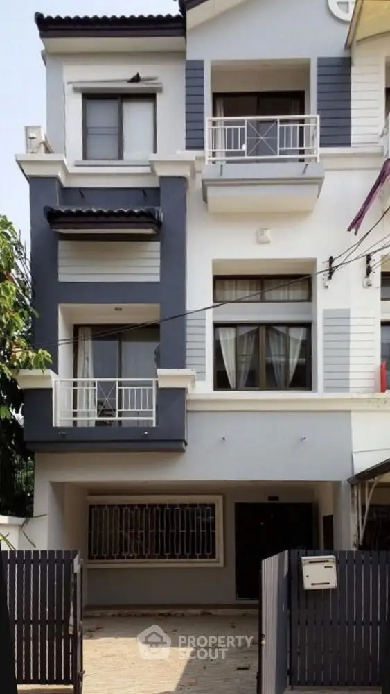 Modern multi-story townhouse with balconies and gated entrance