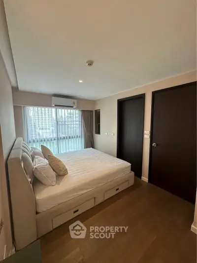Modern bedroom with large window and city view, featuring a comfortable bed and stylish decor.