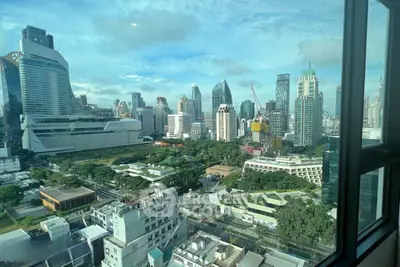 Stunning cityscape view from a high-rise window showcasing modern skyscrapers and lush greenery.