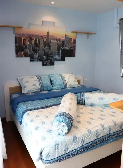 Cozy bedroom with stylish decor and cityscape artwork, featuring a comfortable bed and elegant bedding.