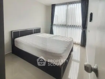 Modern bedroom with large window and minimalist decor in a bright apartment.
