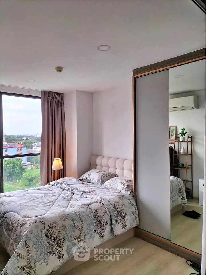 Cozy bedroom with large window and scenic view, featuring a plush bed and mirrored wardrobe.
