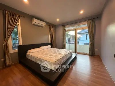 Spacious bedroom with large windows and modern design, featuring a comfortable bed and elegant curtains.