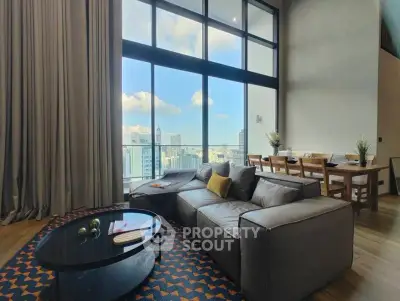 Spacious living room with floor-to-ceiling windows offering stunning city views, modern furniture, and stylish decor.