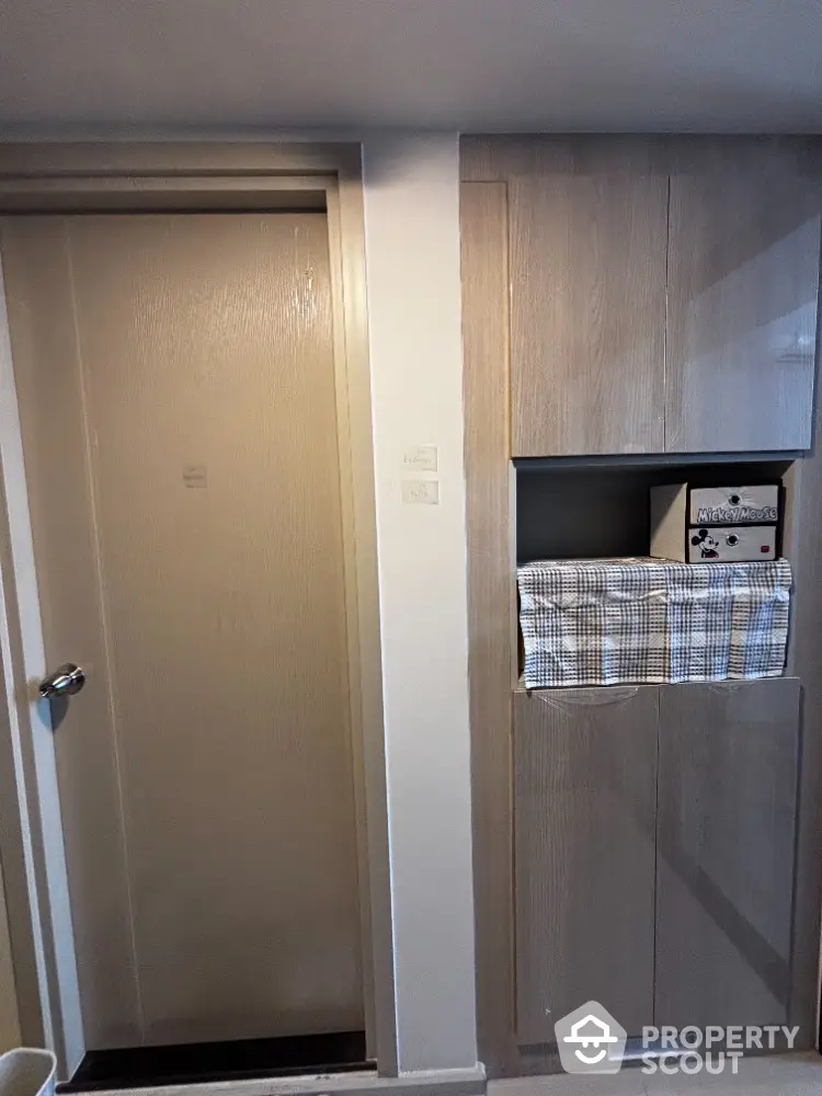 Compact storage area with built-in cabinets and laundry space in modern apartment.