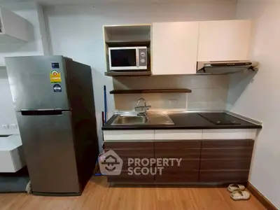 Modern kitchen with sleek cabinets, stainless steel fridge, and built-in microwave.