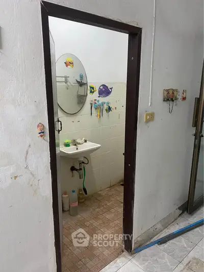 Compact bathroom with wall-mounted sink and mirror, featuring playful fish decals on tiles.