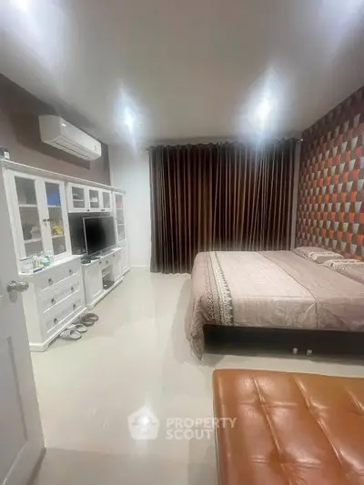 Spacious bedroom with modern decor and ample natural light, featuring a stylish TV unit and comfortable bedding.