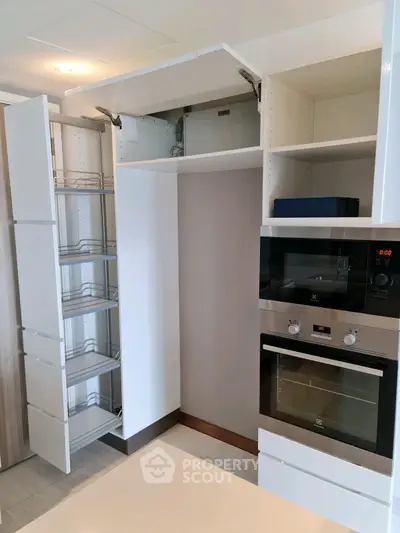 Modern kitchen with sleek cabinetry and built-in oven, showcasing efficient storage solutions.