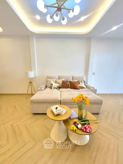 Modern living room with stylish furniture and elegant lighting, featuring a cozy sofa and chic coffee tables.