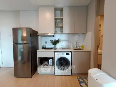 Modern kitchen with sleek appliances and integrated washing machine in stylish apartment.