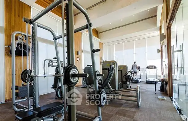 Luxurious gym with modern fitness equipment and floor-to-ceiling windows in upscale residential complex.