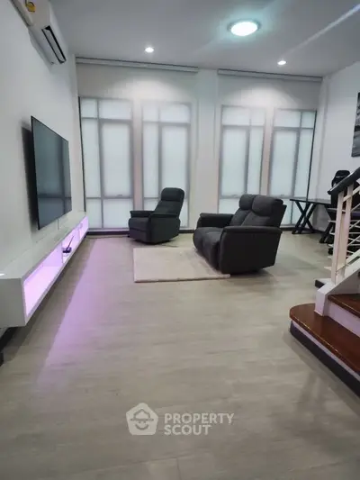 Modern living room with sleek design, featuring cozy recliners and a wall-mounted TV, perfect for relaxation.