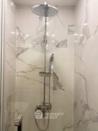 Luxurious marble-tiled shower with modern rain showerhead in elegant bathroom.