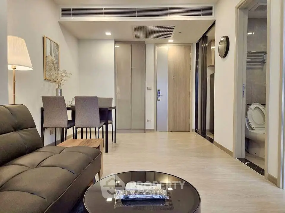 Modern living room with sleek furniture and dining area in a stylish apartment.