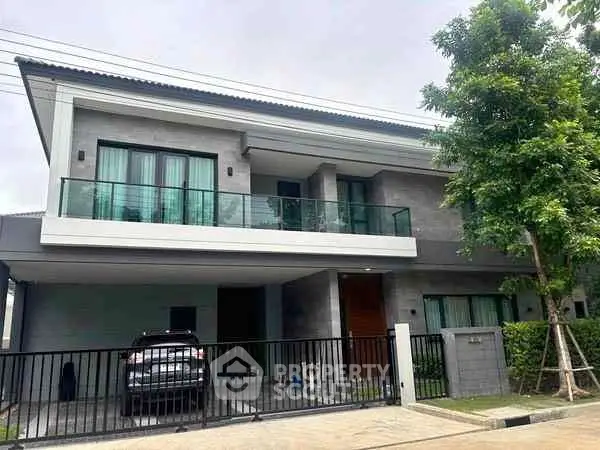 Modern two-story house with balcony and garage in a serene neighborhood.