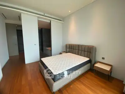 Spacious bedroom with modern design and wooden flooring in luxury apartment.