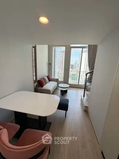 Modern living room with city view, featuring stylish furniture and large windows.