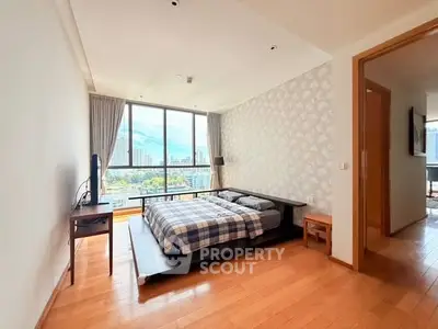 Spacious bedroom with city view and modern decor in high-rise apartment.