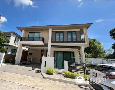 Modern two-story house with balcony and driveway in a sunny neighborhood