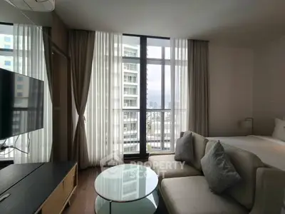 Modern living room with large windows and city view, featuring a cozy sofa and sleek decor.